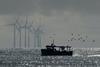 Image of a fishing boat with offshore wind turbines in the background