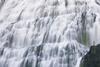 Very small person in red looking at a large waterfall