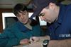 Coast Guard Petty Officer 3rd Class Dan Jarrett, of Marine Safety Detachment Kodiak, goes over the results of the dockside safety exam with the captain of the fishing vessel Castle Cape, Steve Eggemeyer in 2006. Credit: Petty Officer Paul Roszkowski