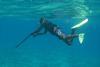 A Papua New Guinean spear fisherman loading a rifle-style spear gun at the surface. These spear guns are normally hand carved wooden stocks with rubber slings that fire a thin metal rod that has been hand sharpened.