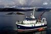 A survey vessel on the west coast of Scotland with a salmon farm in the background