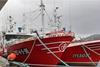 Two red and white fishing vessels at port