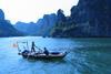 Vietnamese fishing boat with two fishers and cliffs in the background