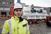 Arild Vikan, project manager at Salmon Evolution, in hi viz and hard hat standing in front of a heat pump being transported on a lorry