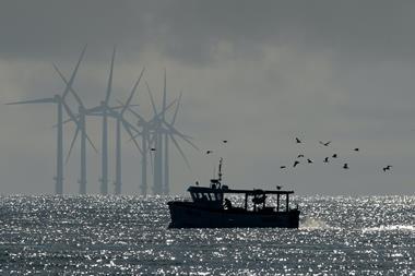 Image of a fishing boat with offshore wind turbines in the background