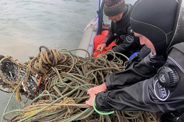 Divers hauling in ghost gear on to a vessel
