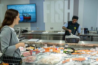 A shopper at a Waitrose fish counter with an employee weighing a seabass
