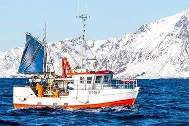 The image shows a Norwegian fishing vessel on the water with the snowy coastline in the background
