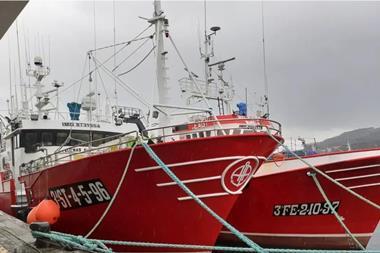 Two red and white fishing vessels at port