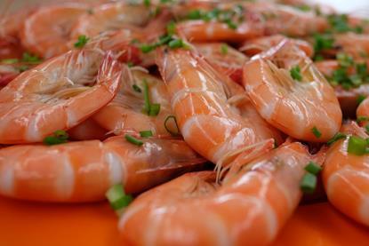 The image shows cooked fresh prawns on a plate seasoned with parsley