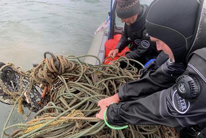 Divers hauling in ghost gear on to a vessel