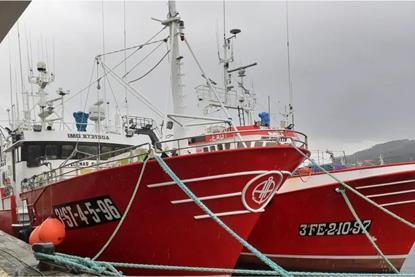 Two red and white fishing vessels at port