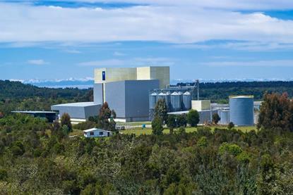 Image of BioMar's feed production factory in Ercilla, Chile with trees in the foreground, mountains in the back on a sunny day