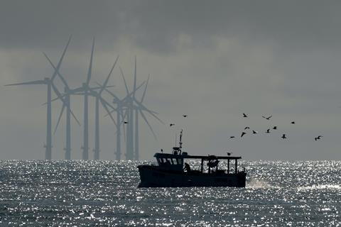 Image of a fishing boat with offshore wind turbines in the background