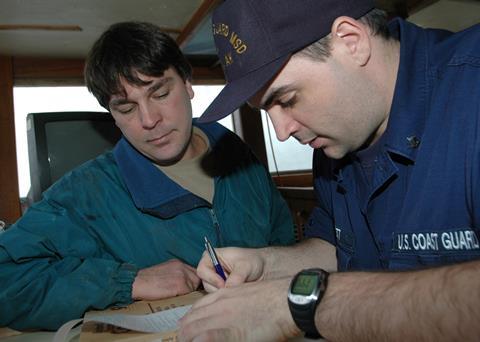 Coast Guard Petty Officer 3rd Class Dan Jarrett, of Marine Safety Detachment Kodiak, goes over the results of the dockside safety exam with the captain of the fishing vessel Castle Cape, Steve Eggemeyer in 2006. Credit: Petty Officer Paul Roszkowski