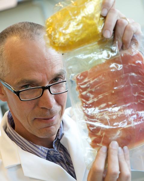 Professor Andrew Mills with food packaging incorporating the intelligent plastic indicator.  The yellow part is the indicator and it has changed colour to show that the food it contains has spoiled.